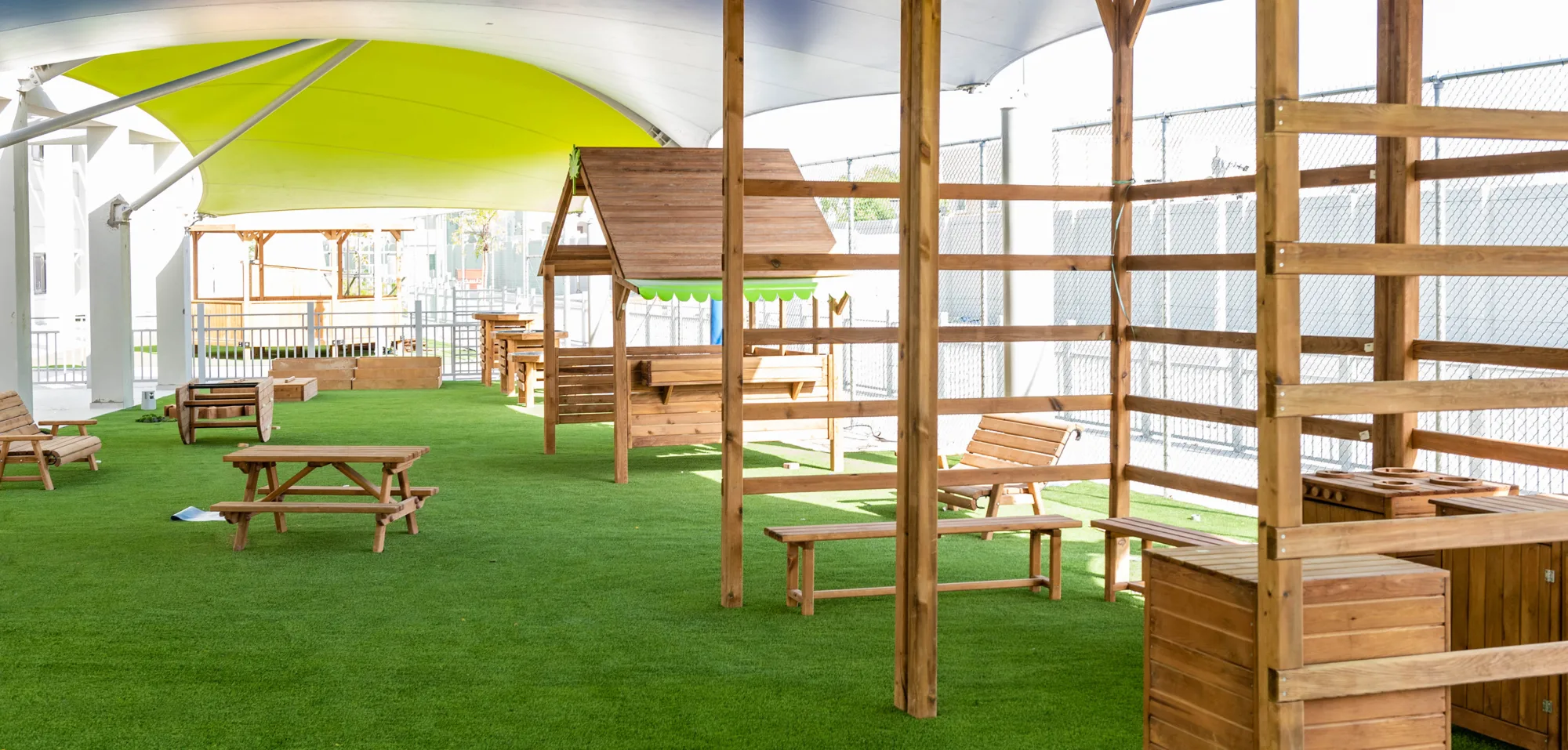 Doha College play area with grassy landscape and furnitures made out of wood