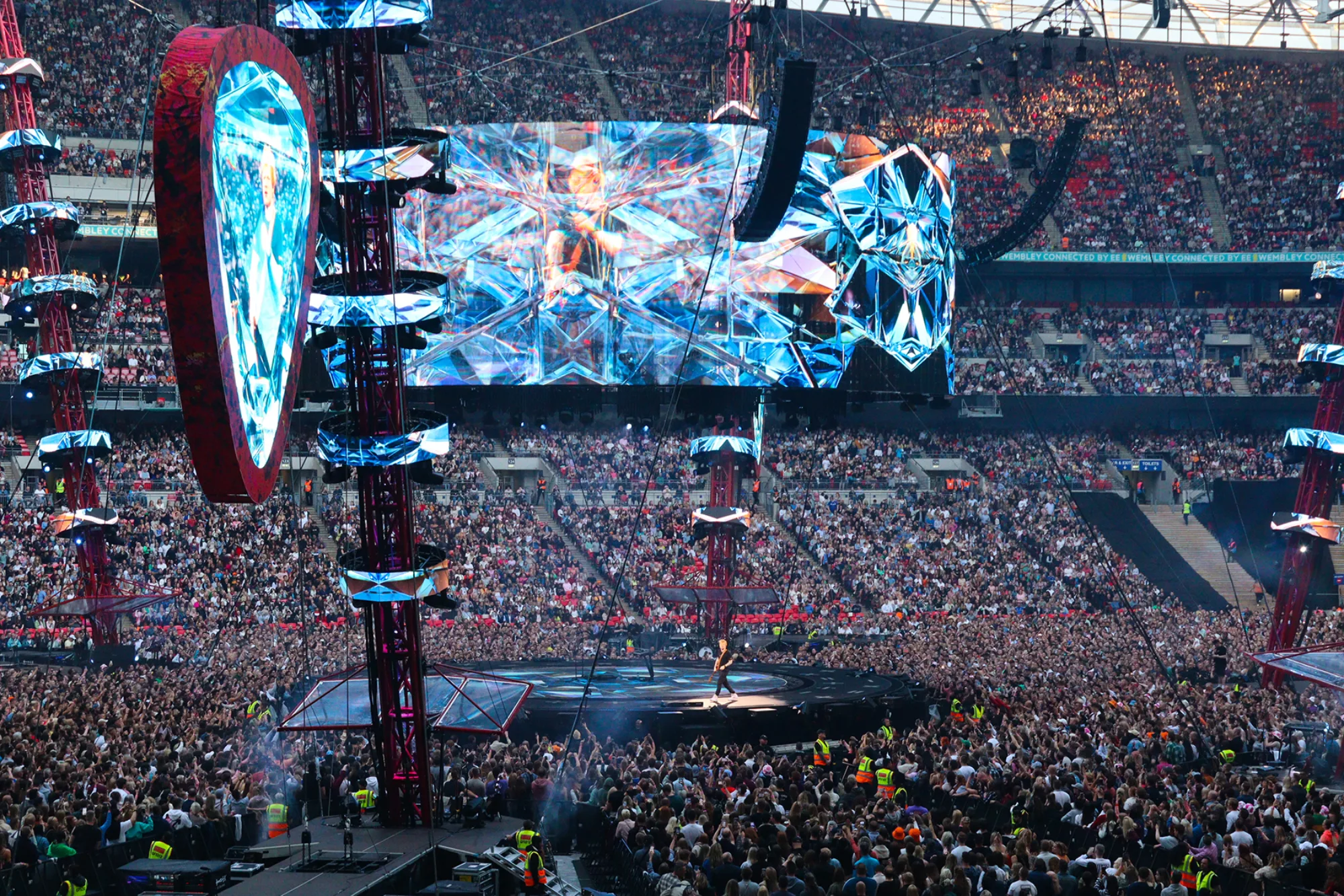 Ed Sheeran on stag with structural podium and thousands of fans surrounding