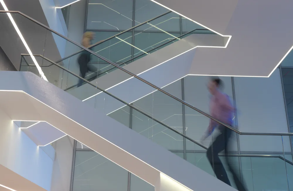 Staircase light in office atrium with staff walking up