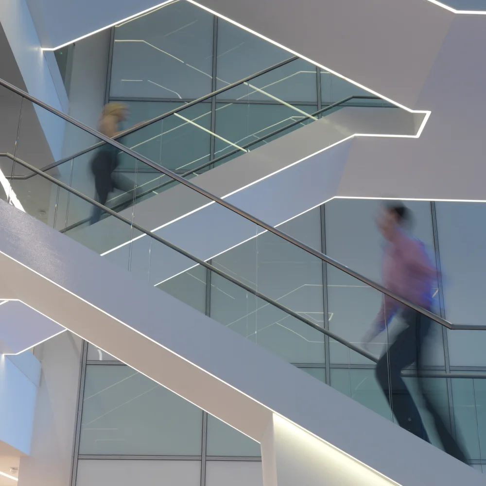Staircase light in office atrium with staff walking up