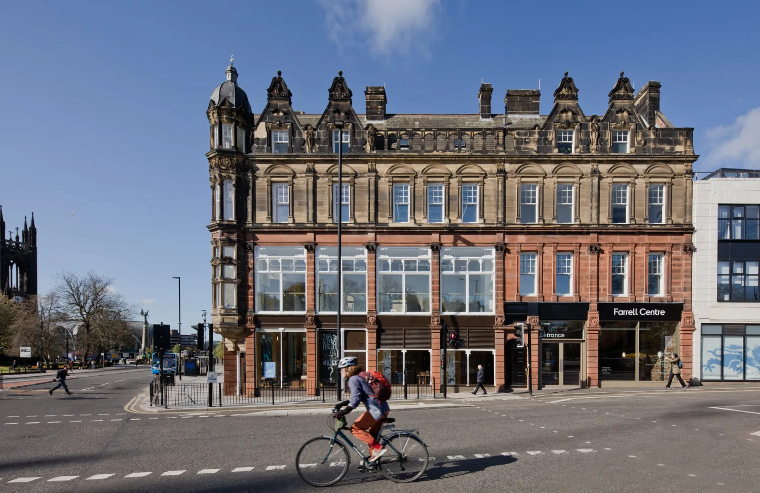 Front facade of building with cyclist on road in front