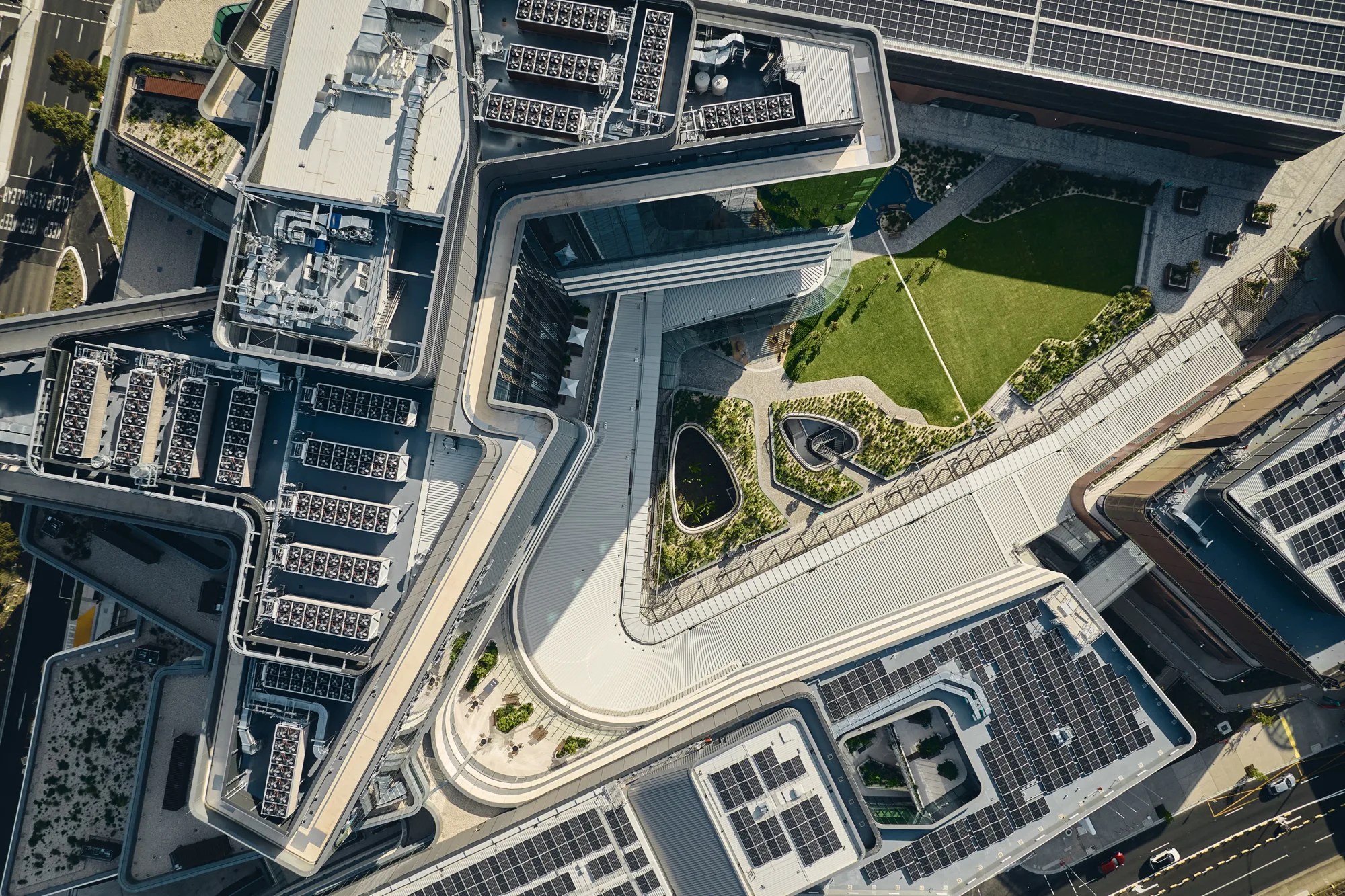 Aerial view of a large building complex with rooftop solar panels, mechanical plant equipment and landscaped courtyard spaces