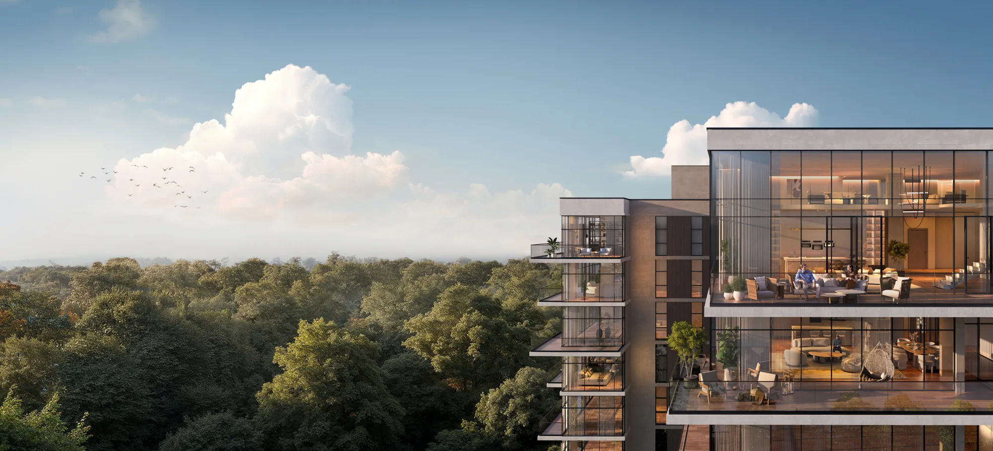 A cropped panoramic view of contemporary multi-storey residential buildings with large glass windows and balconies overlooking a dense forest canopy, beneath a blue sky with clouds and birds in the distance.