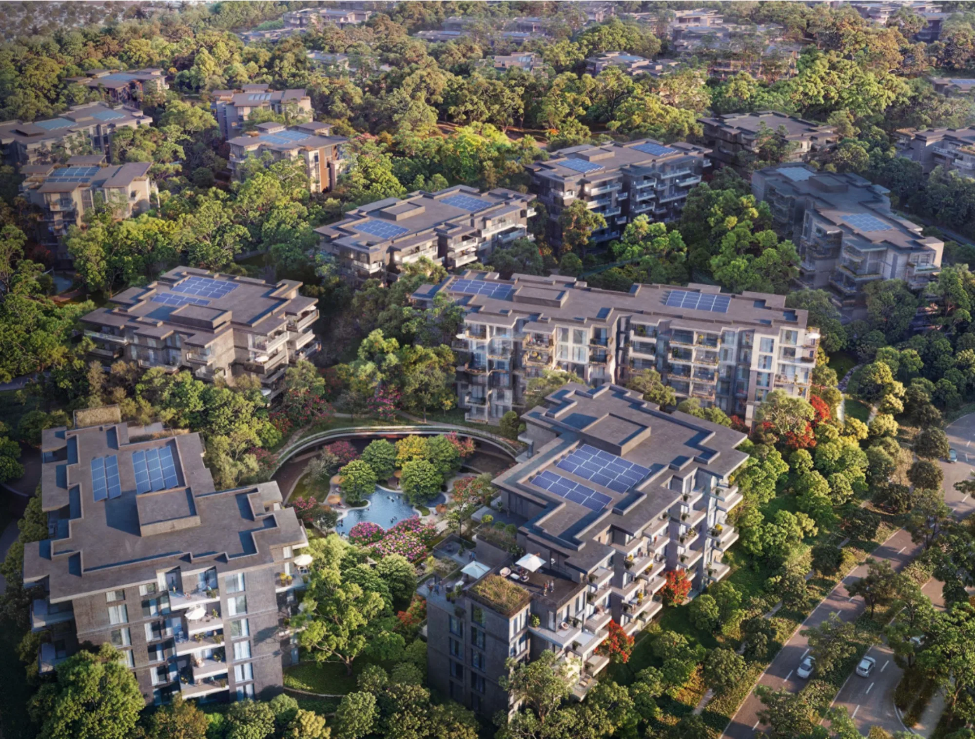 Aerial view of multiple mid-rise residential buildings with flat roofs and solar panels, arranged among dense trees, internal roads, and a central landscaped courtyard with a small water feature.