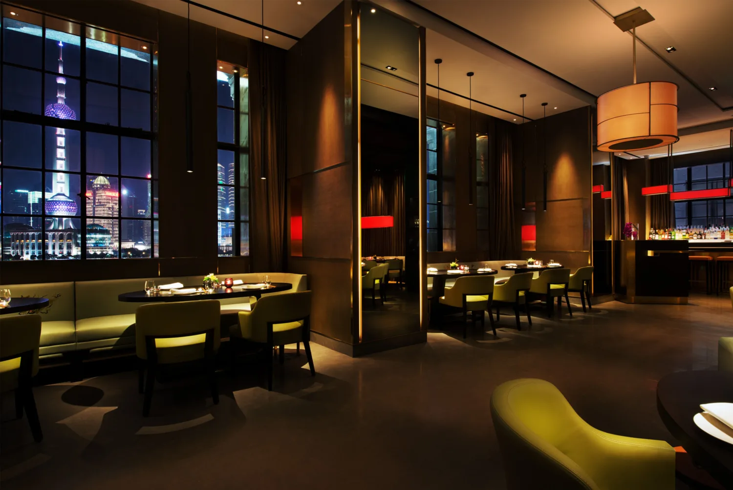 Main restaurant area with multiple dining tables and large windows featuring night view of Shanghai’s city skyline