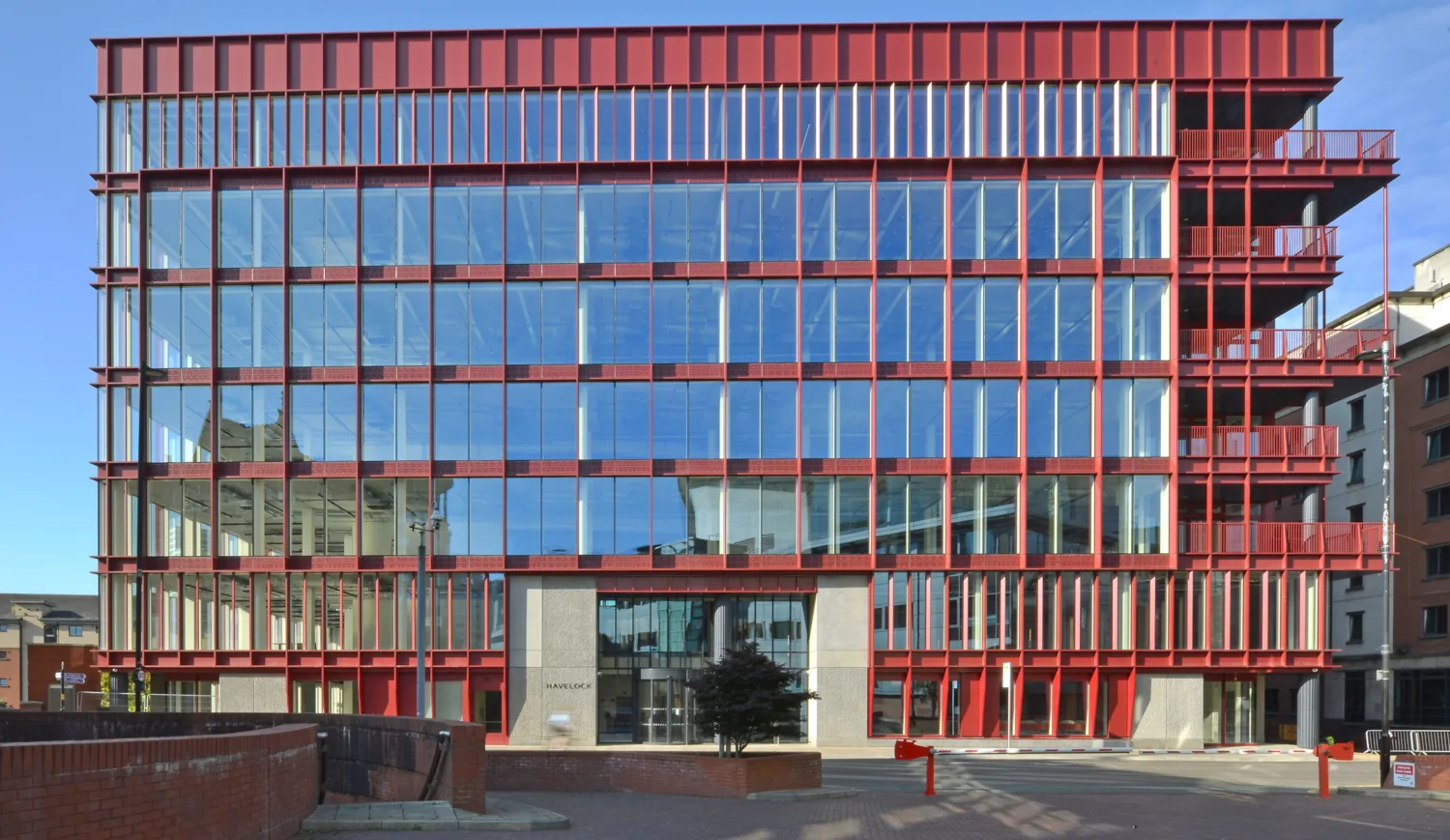 View of front elevation of building, red cladding and windows, against a blue sky