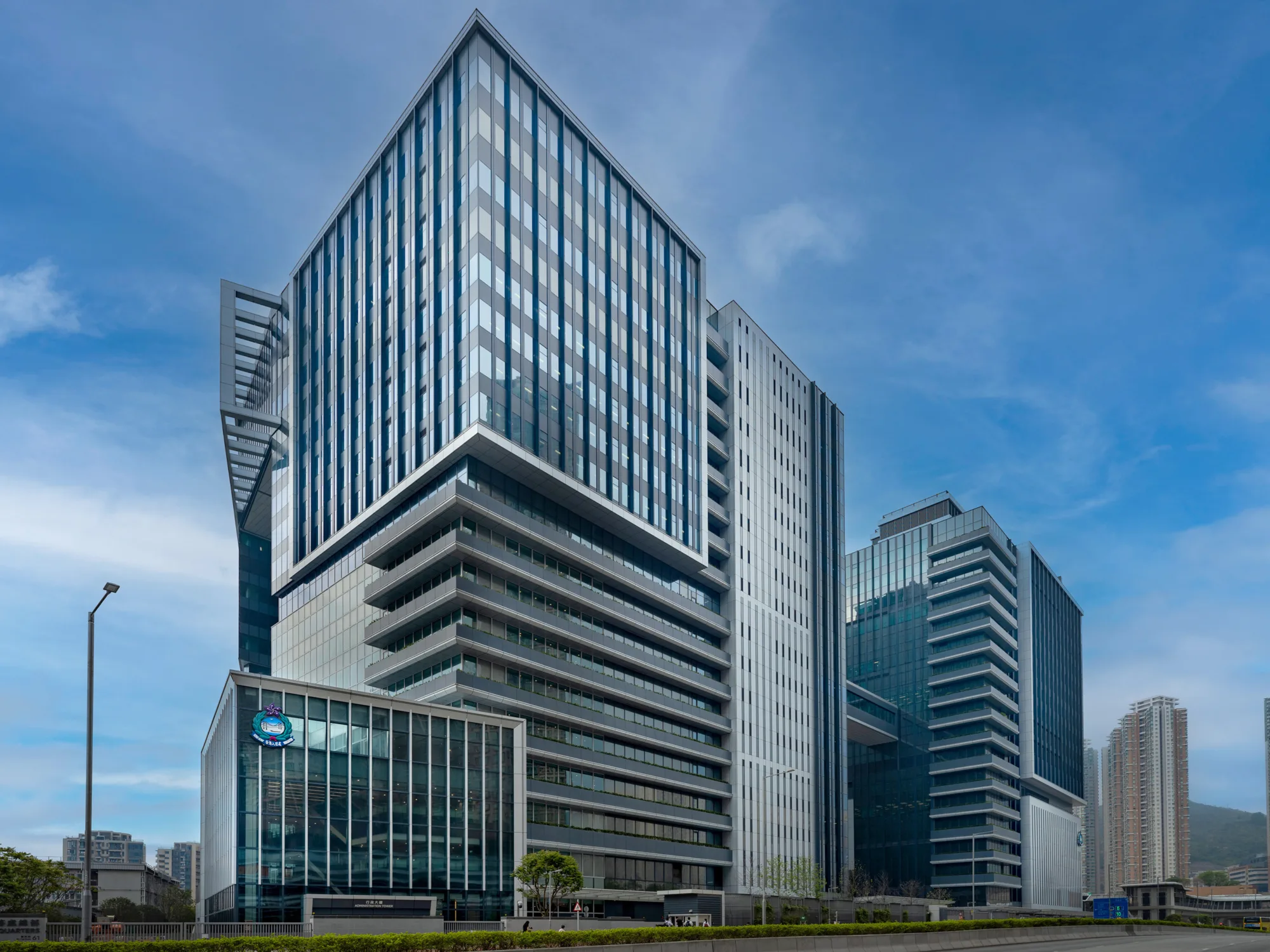 Cityscape with tall glass office buildings under a clear blue sky; the largest building has an angular design with horizontal lines.