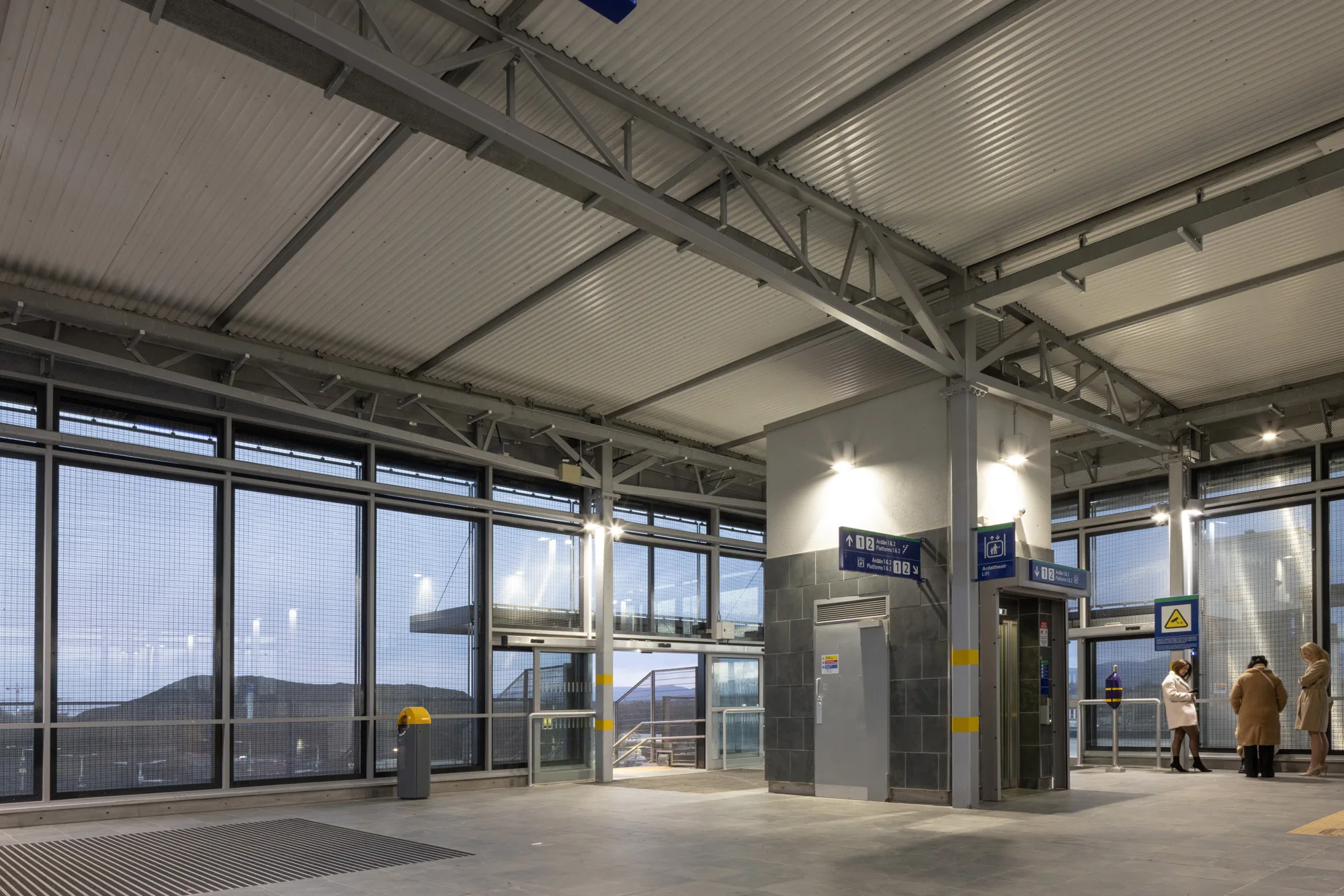 Illuminated interior of Kisoge station with a small crowd on the side