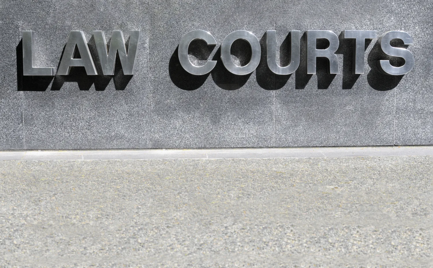 Close up metal lettering of LAW COURTS on grey concrete side of building