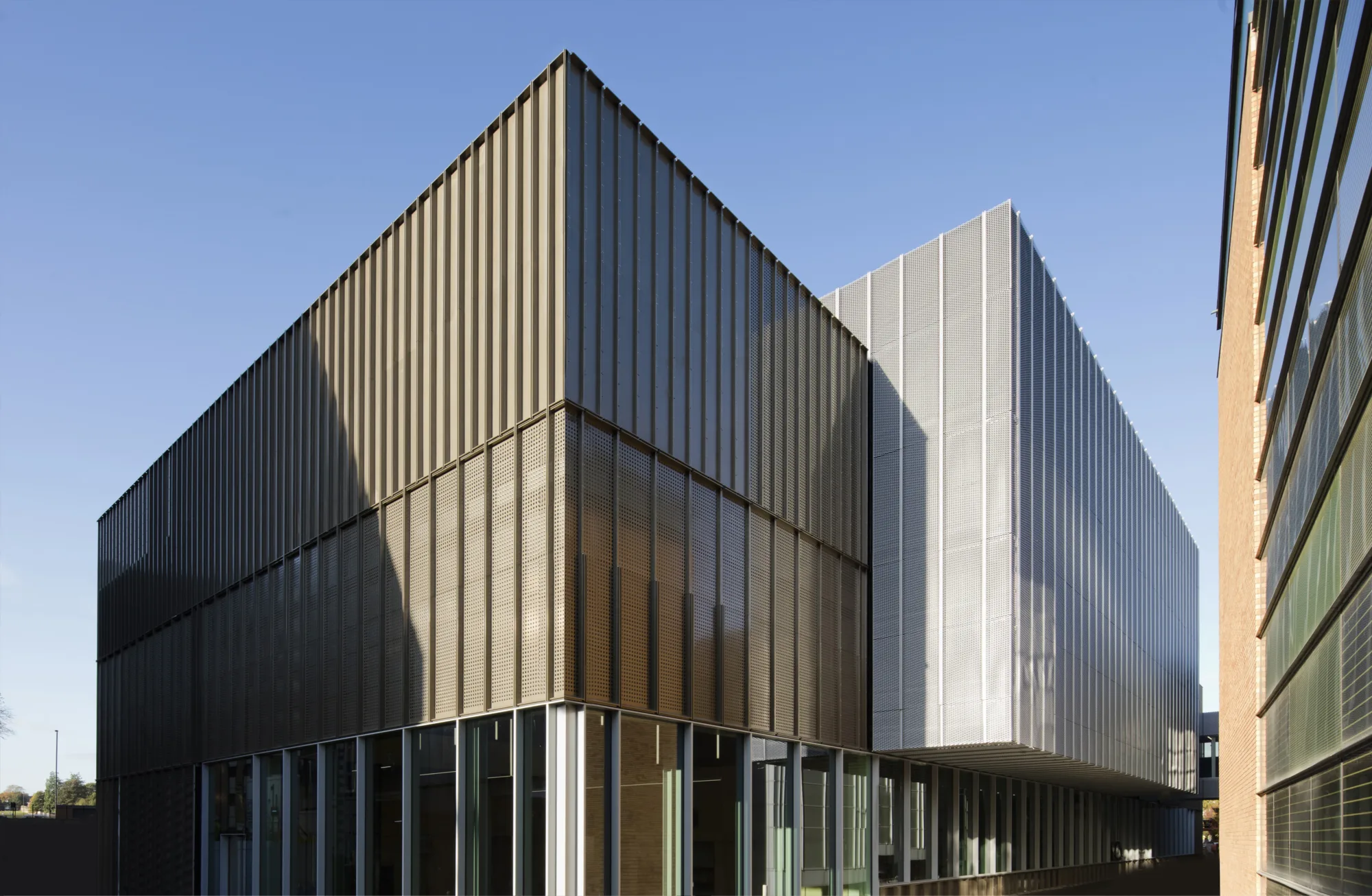 Exterior of modern sports hall, dark grey building against a blue sky