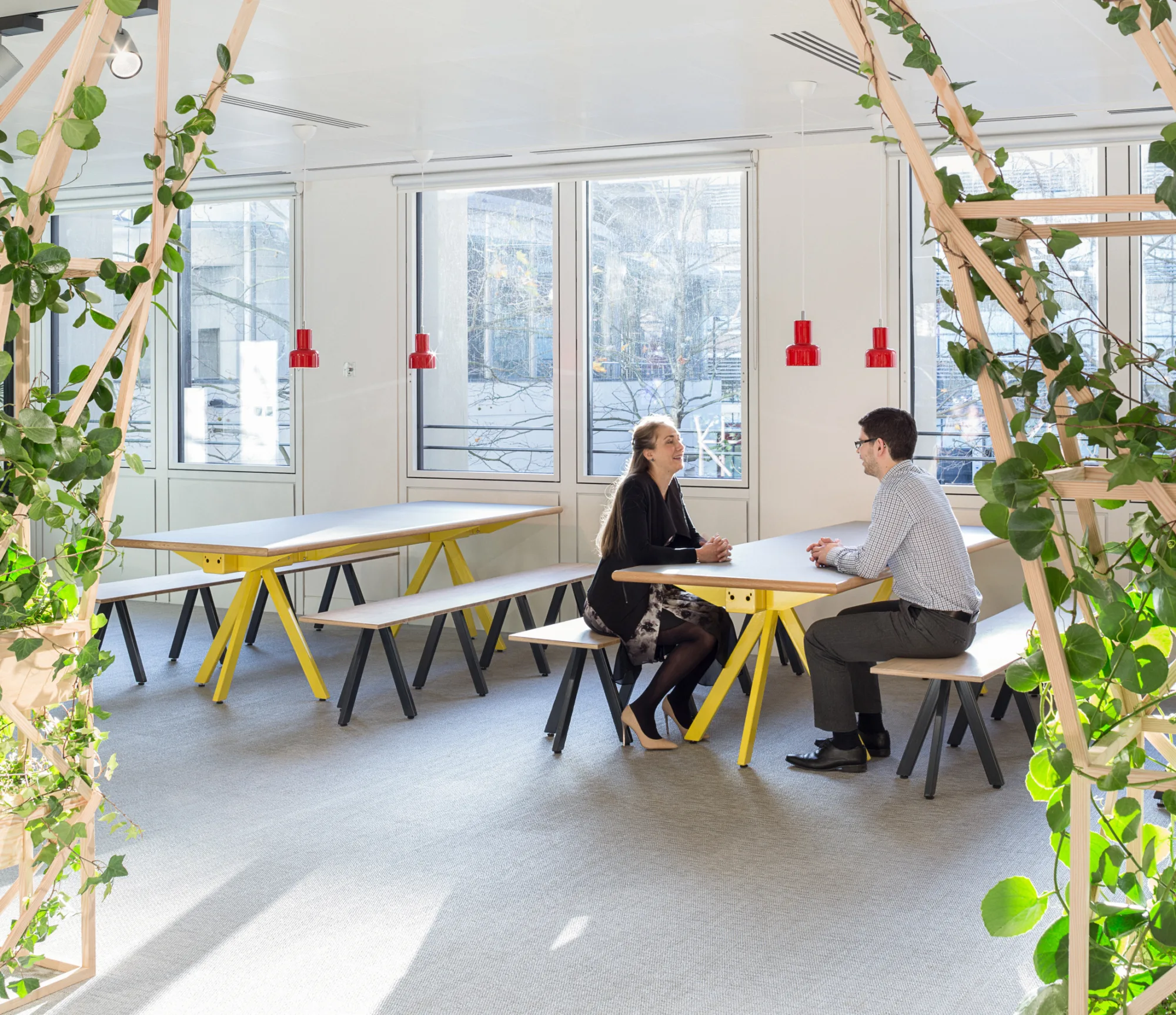 Two people sat on communal picnic tables in a bright office