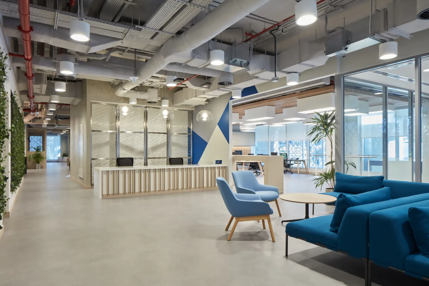PWC Middle East large reception area with blue sofas and live pants as decoration.