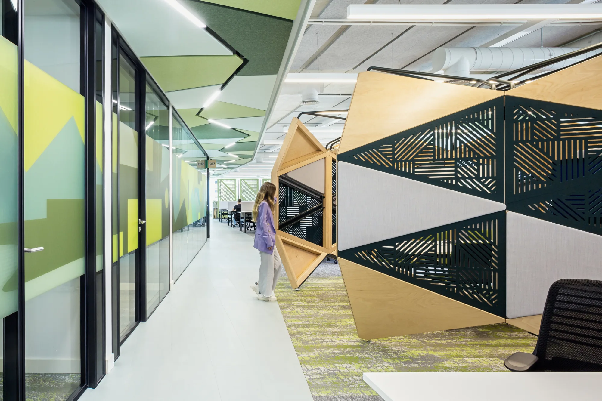 Office walkway with glass fronted meeting rooms and panelling on the right for open meeting spaces