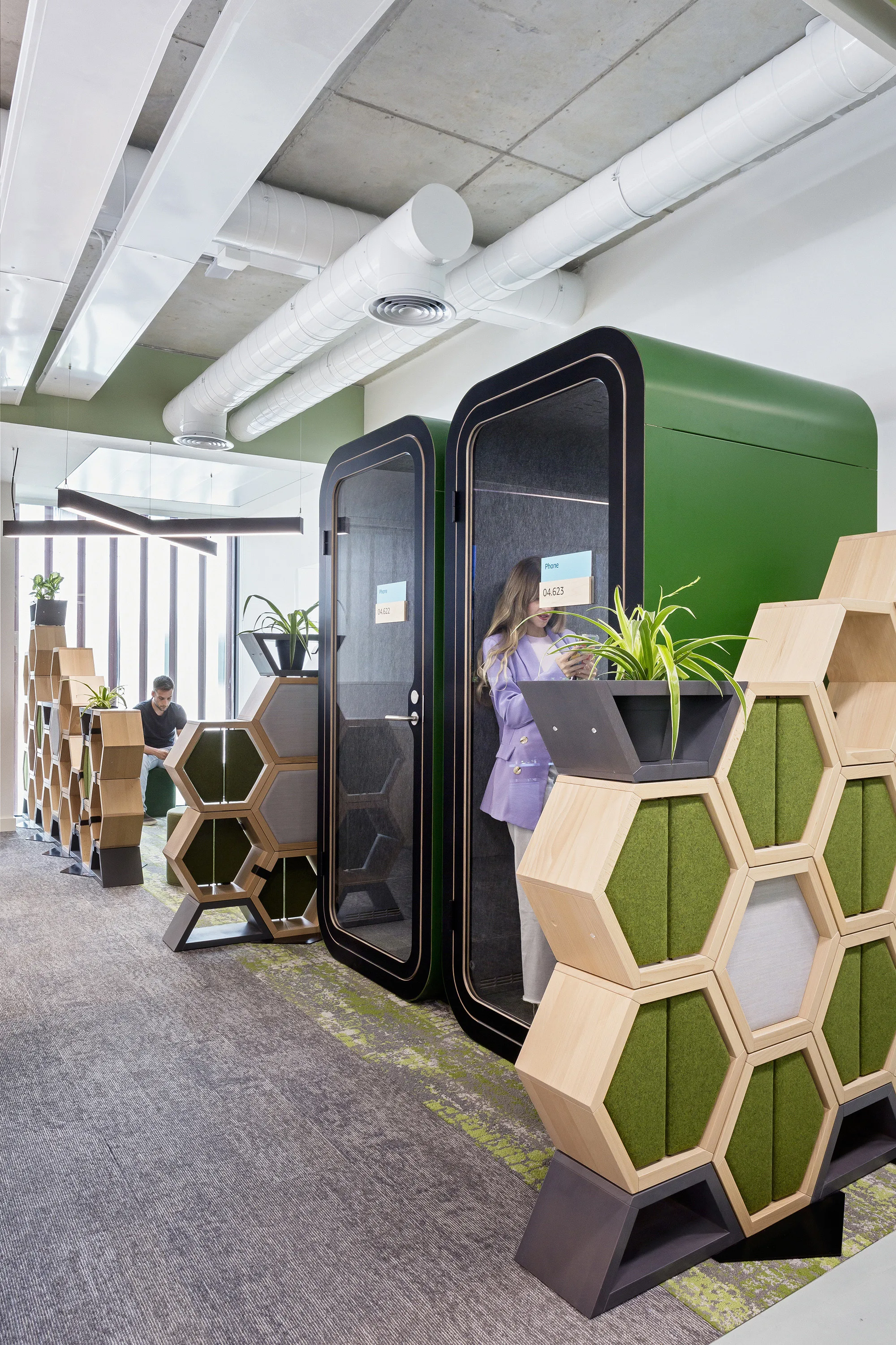 Office area with phone booths for private chats with glass fronts and planting surrounding