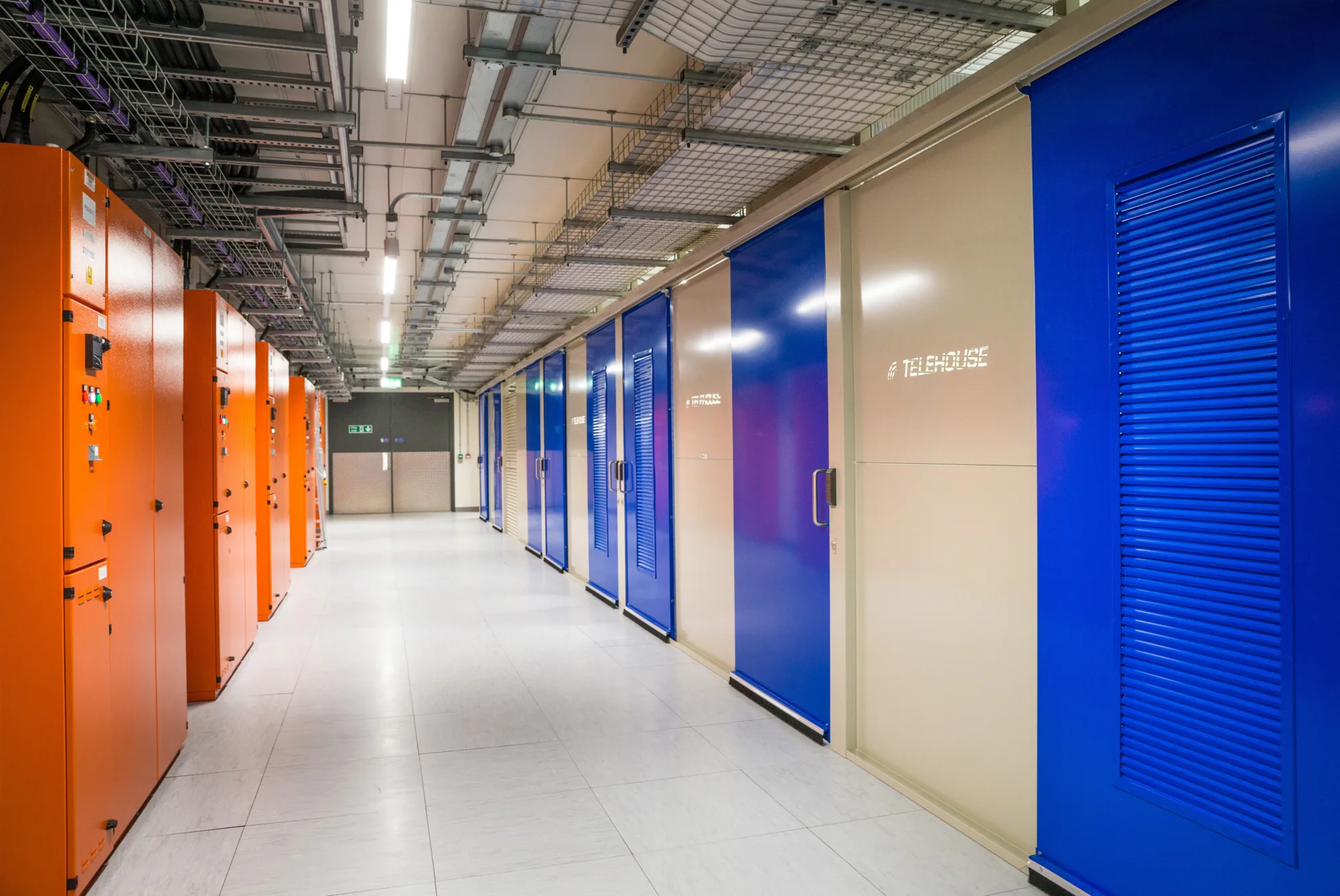 Image of corridor with orange data units on the left and blue doors on the right