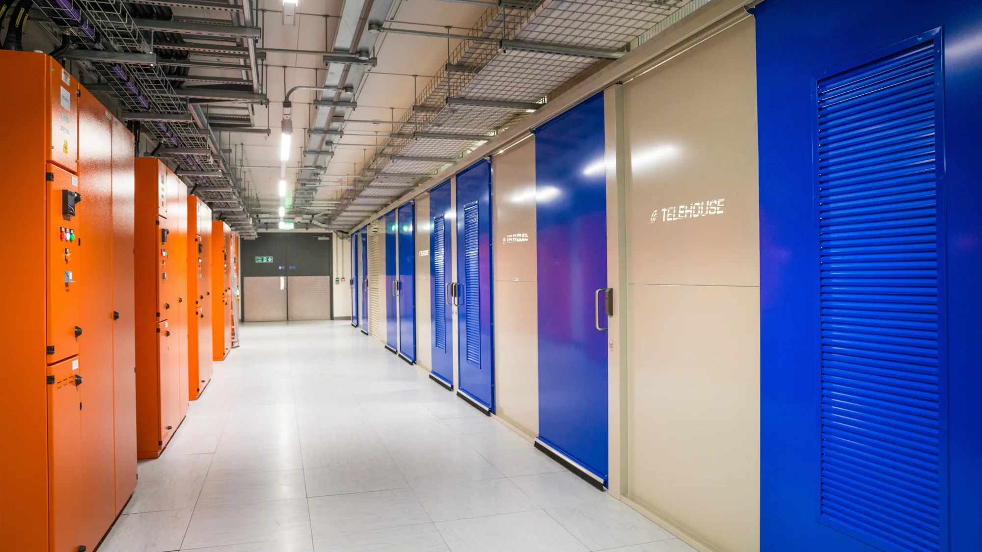 Image of corridor with orange data units on the left and blue doors on the right