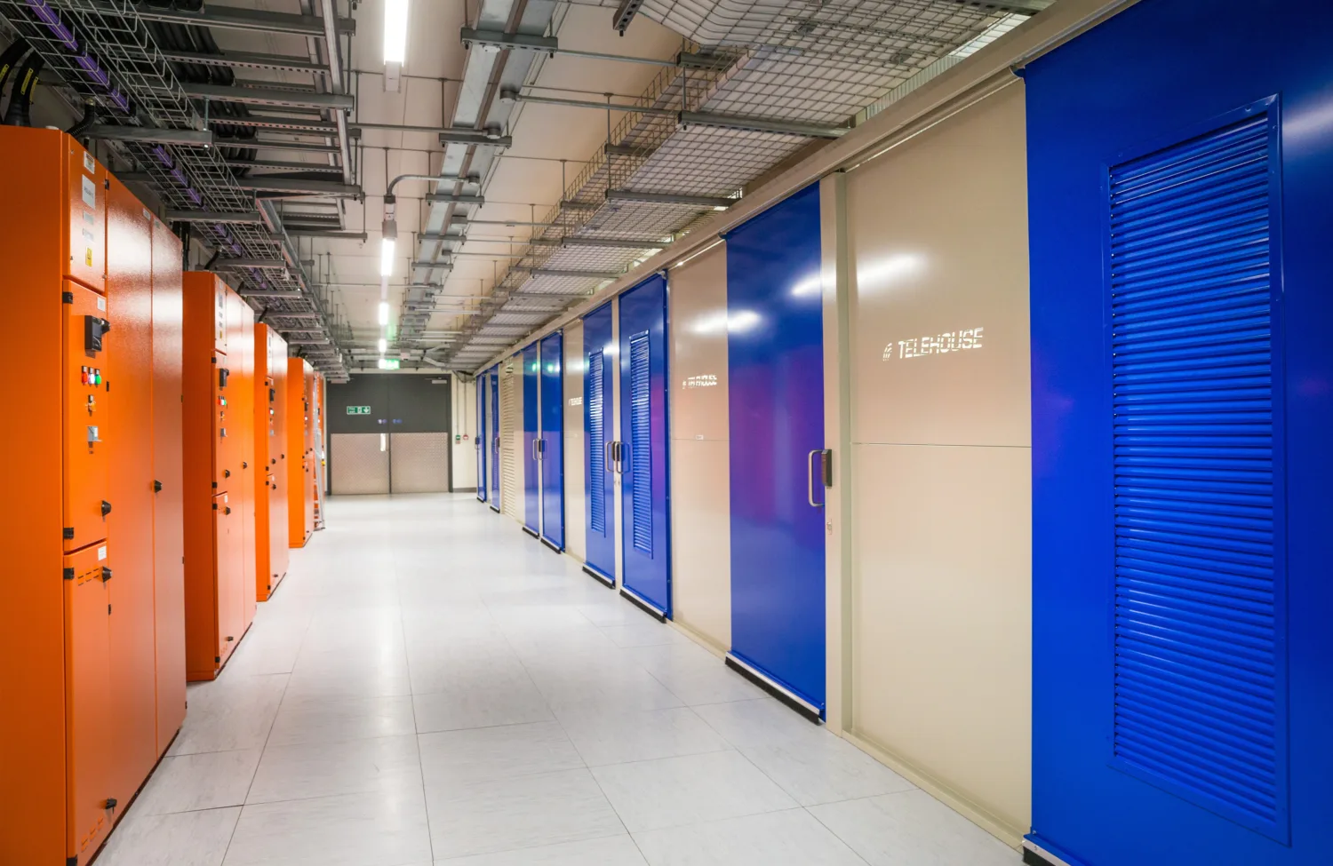 Image of corridor with orange data units on the left and blue doors on the right