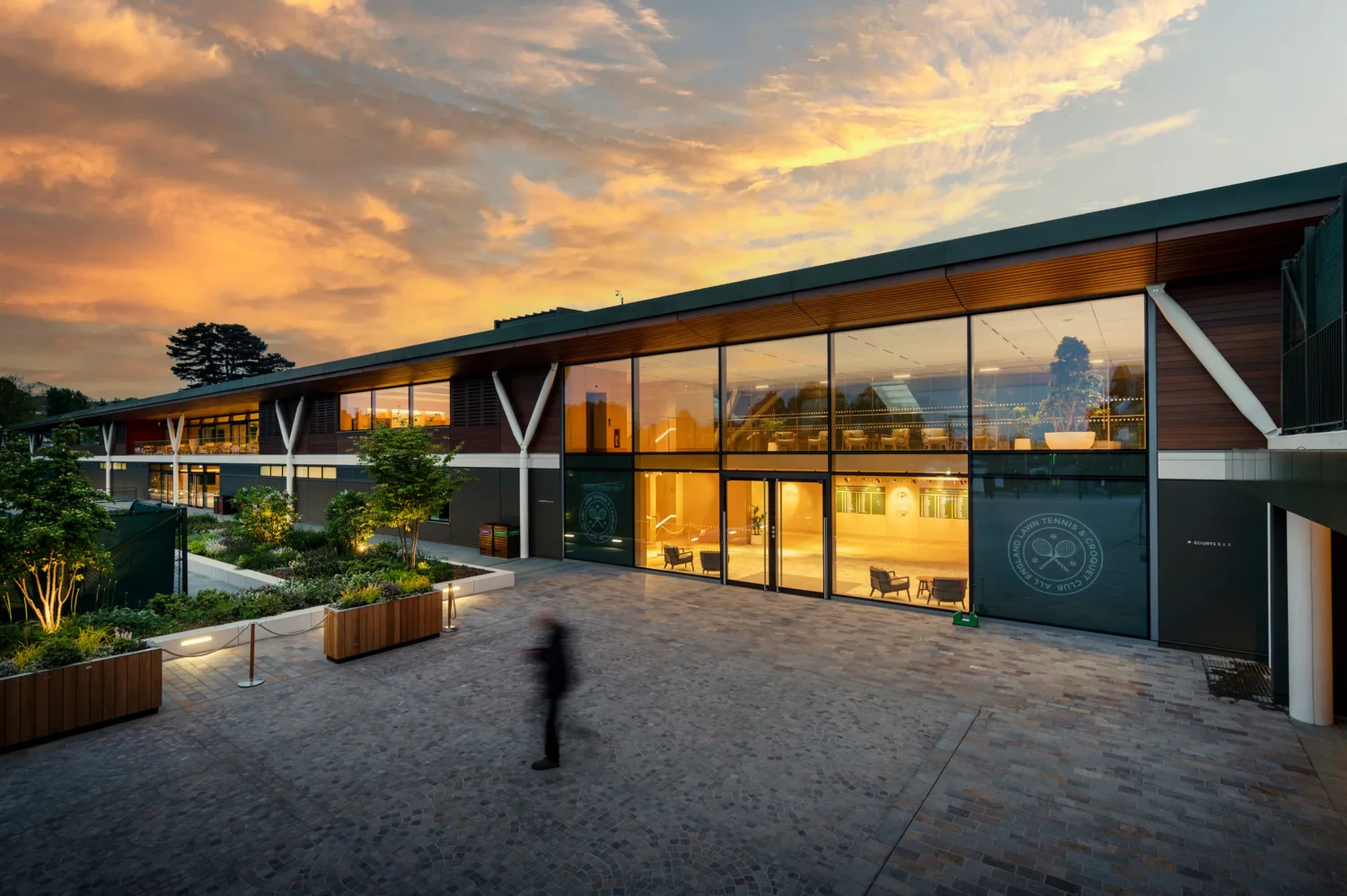 Exterior view of the Tennis Centre at dusk with warm orange lighting
