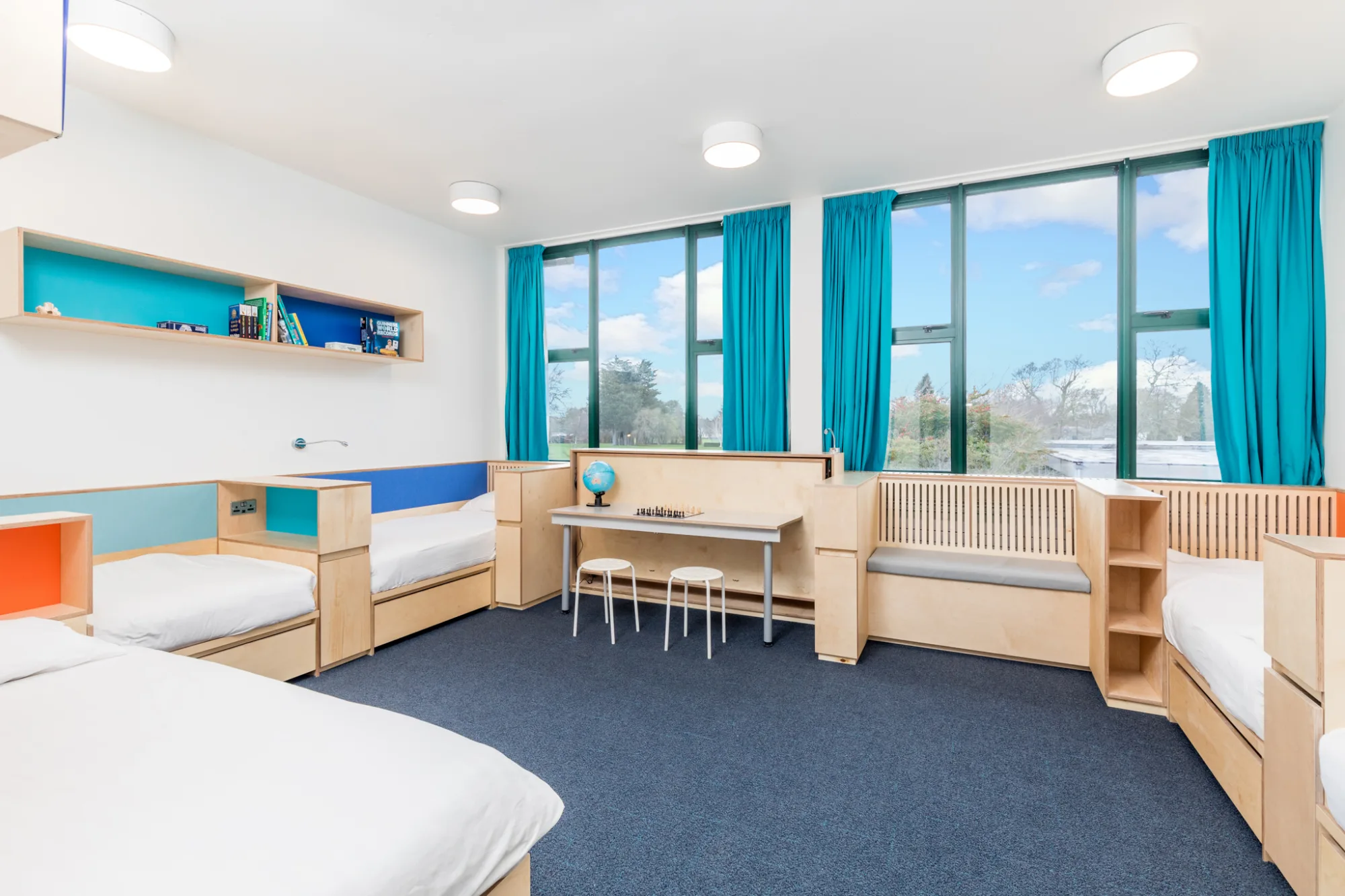 Room with beds, a shelf and blue curtains