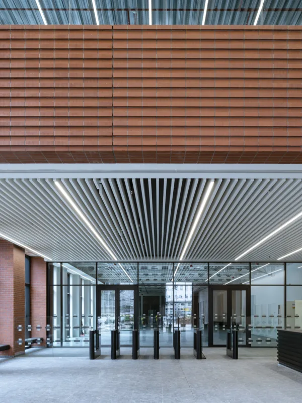 Internal lobby with red bricked walls and a glass doored lobby and grey carpet