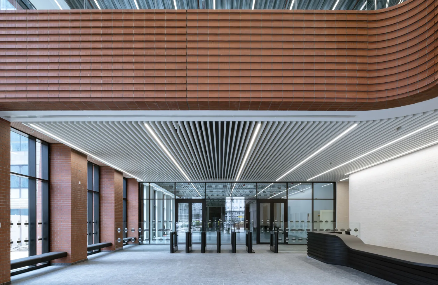 Internal lobby with red bricked walls and a glass doored lobby and grey carpet