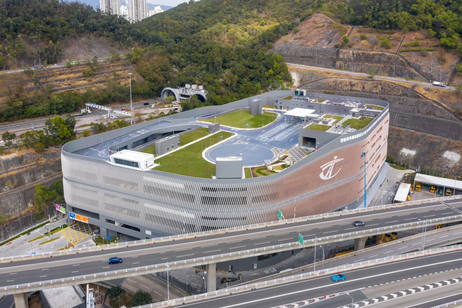 Drone shot of the exterior of the building, with a road system and green space on the roof