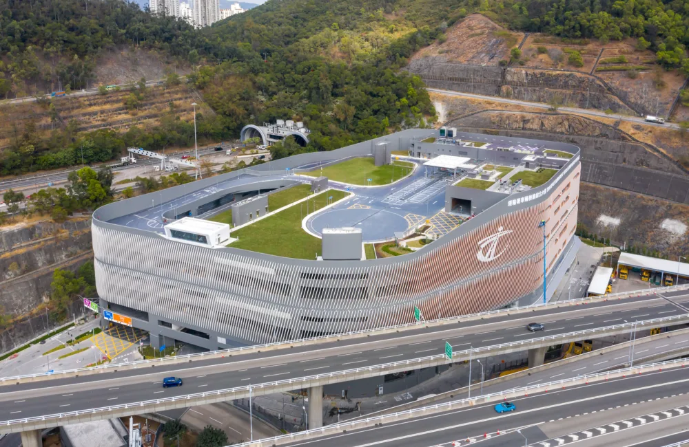Drone shot of the exterior of the building, with a road system and green space on the roof