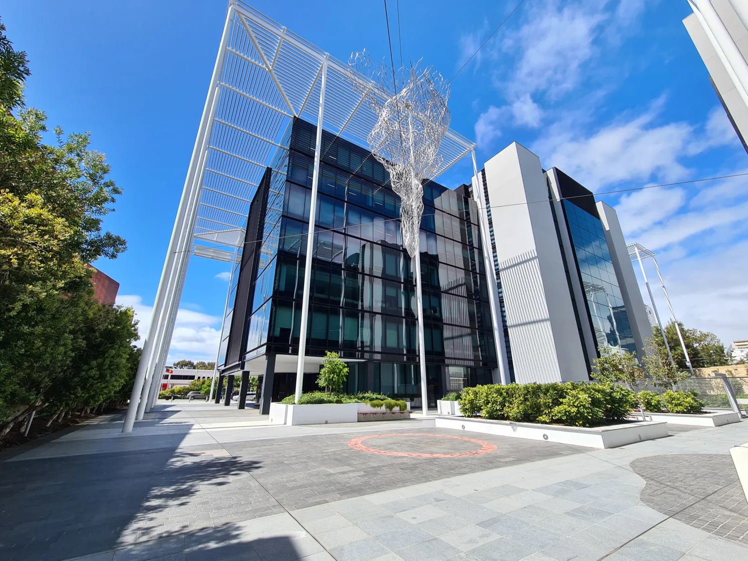 Metalwork sculpture suspended in front of building.