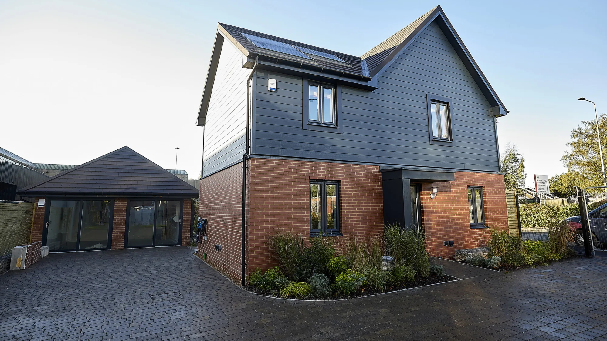 Detached house with 2 downstairs and 2 upstairs windows surrounded by a dark brick driveway