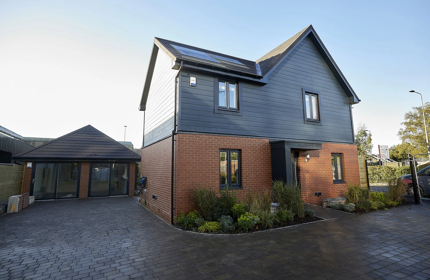 Detached house with 2 downstairs and 2 upstairs windows surrounded by a dark brick driveway