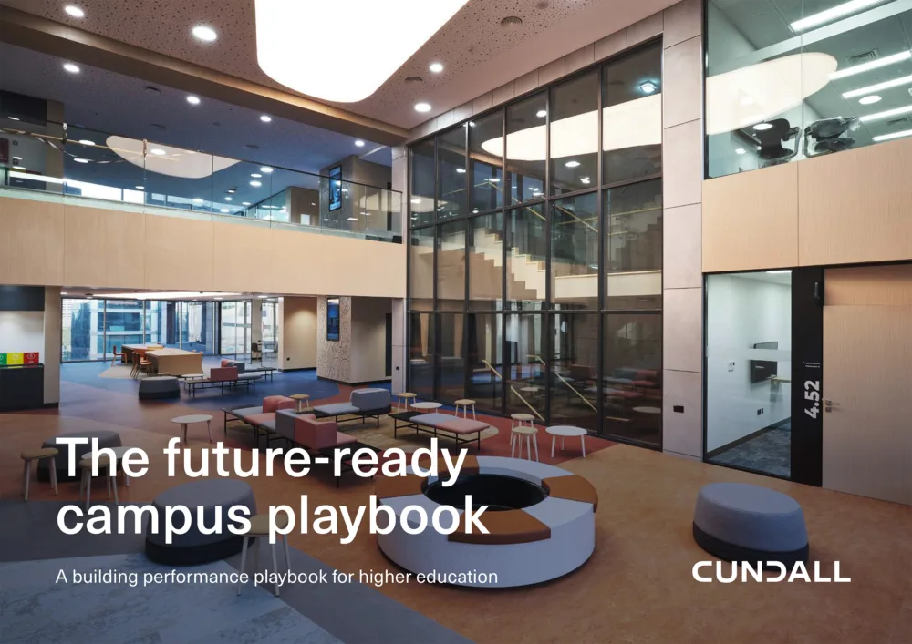 Modern atrium interior with glass walls, staircase, and assorted seating in a lobby area. Overlaid text reads “The future-ready campus playbook” and “A building performance playbook for higher education,” with “CUNDALL” in the lower right.