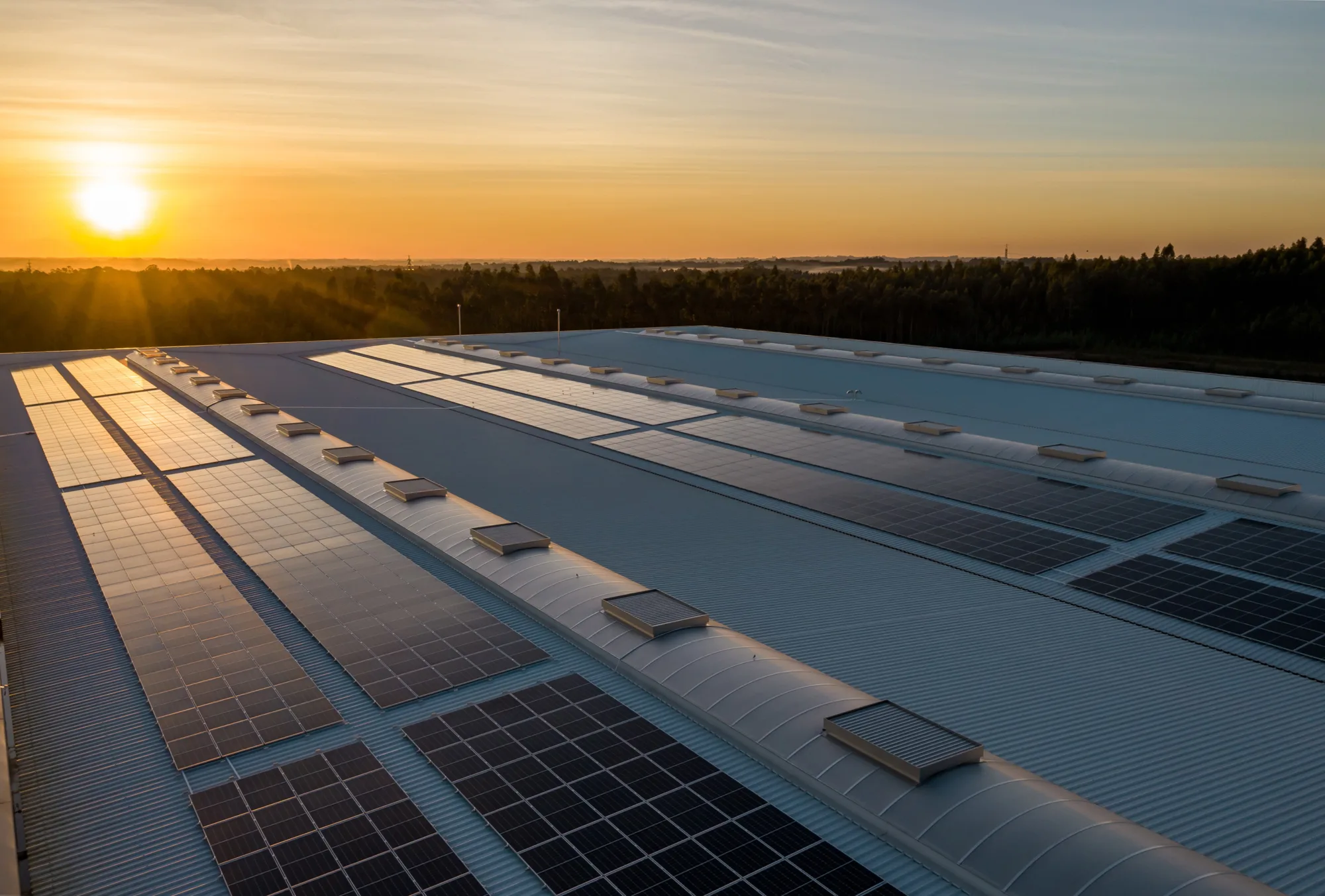Roof mounted solar panels with the sun setting in the distance