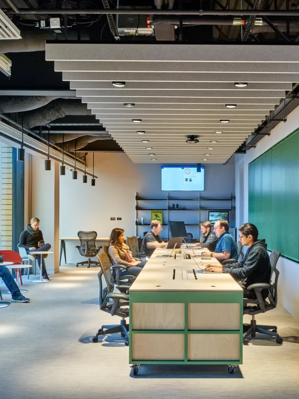 People hotdesking on one large desk and small individual desks at Google offices in 6 Pancras Square
