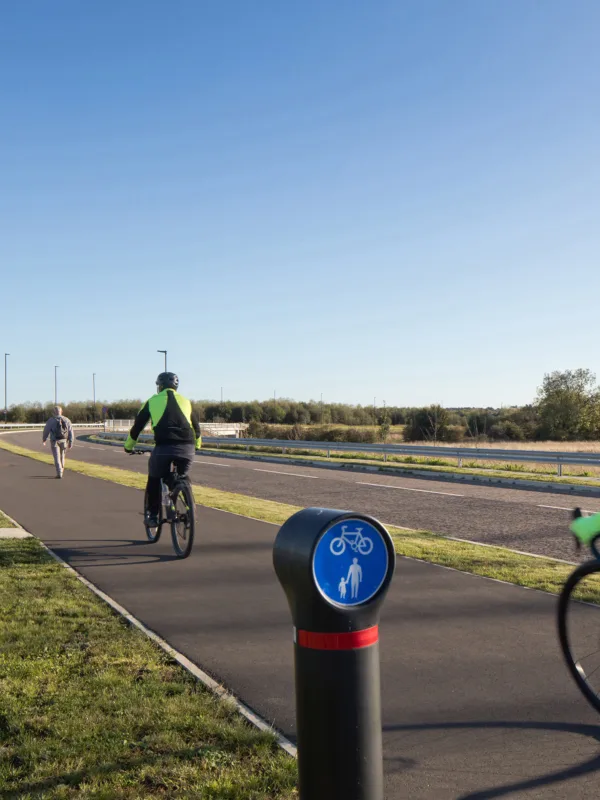 2 cyclist wearing high vis on cycle lane on a bright day with blue sky