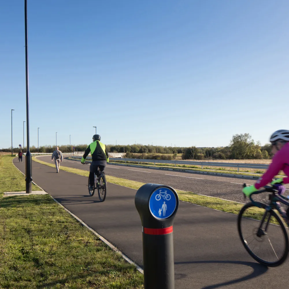 2 cyclist wearing high vis on cycle lane on a bright day with blue sky