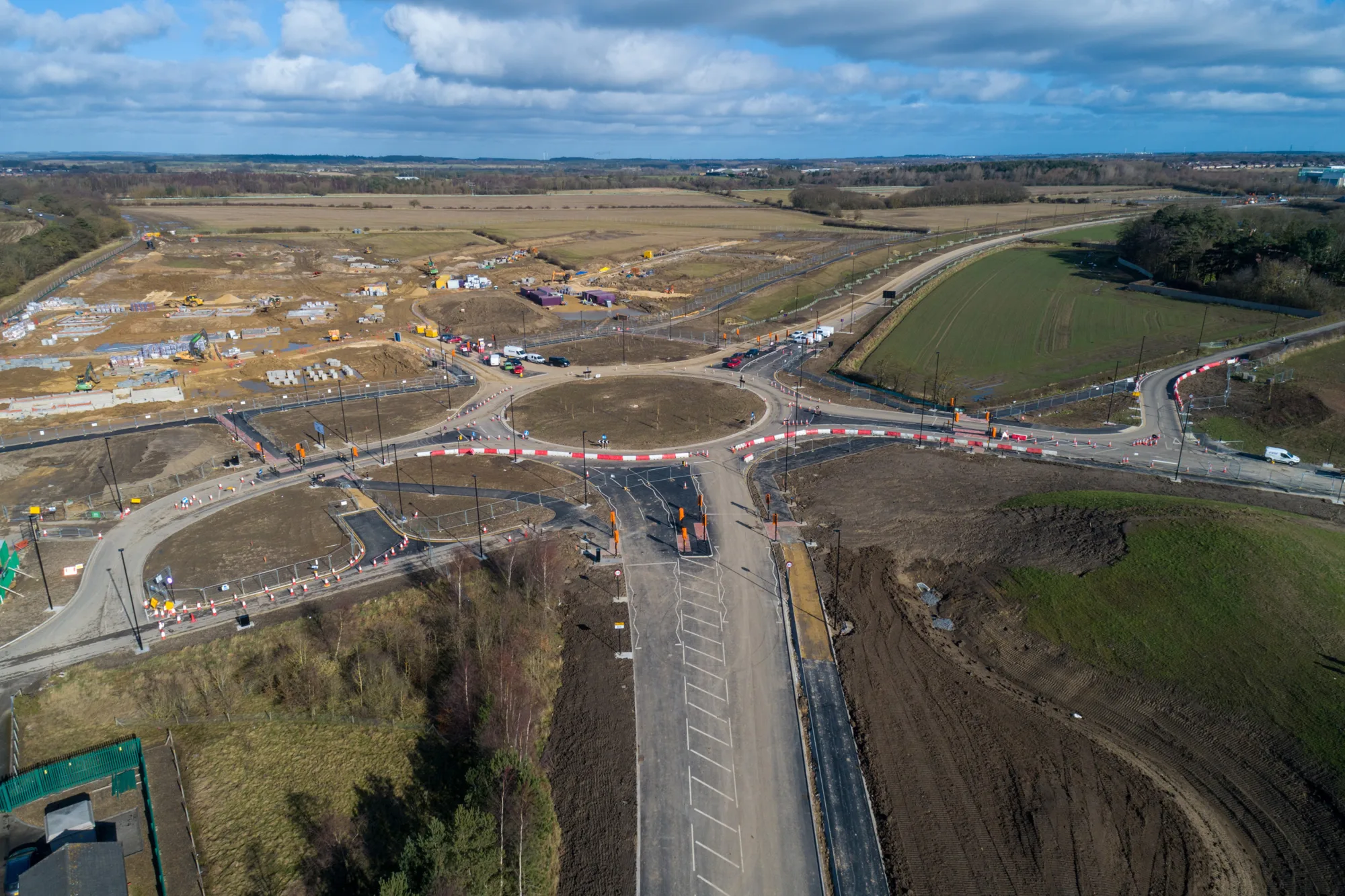 Blue skies with fields and roads under infrastructure at NGP Spine Road.