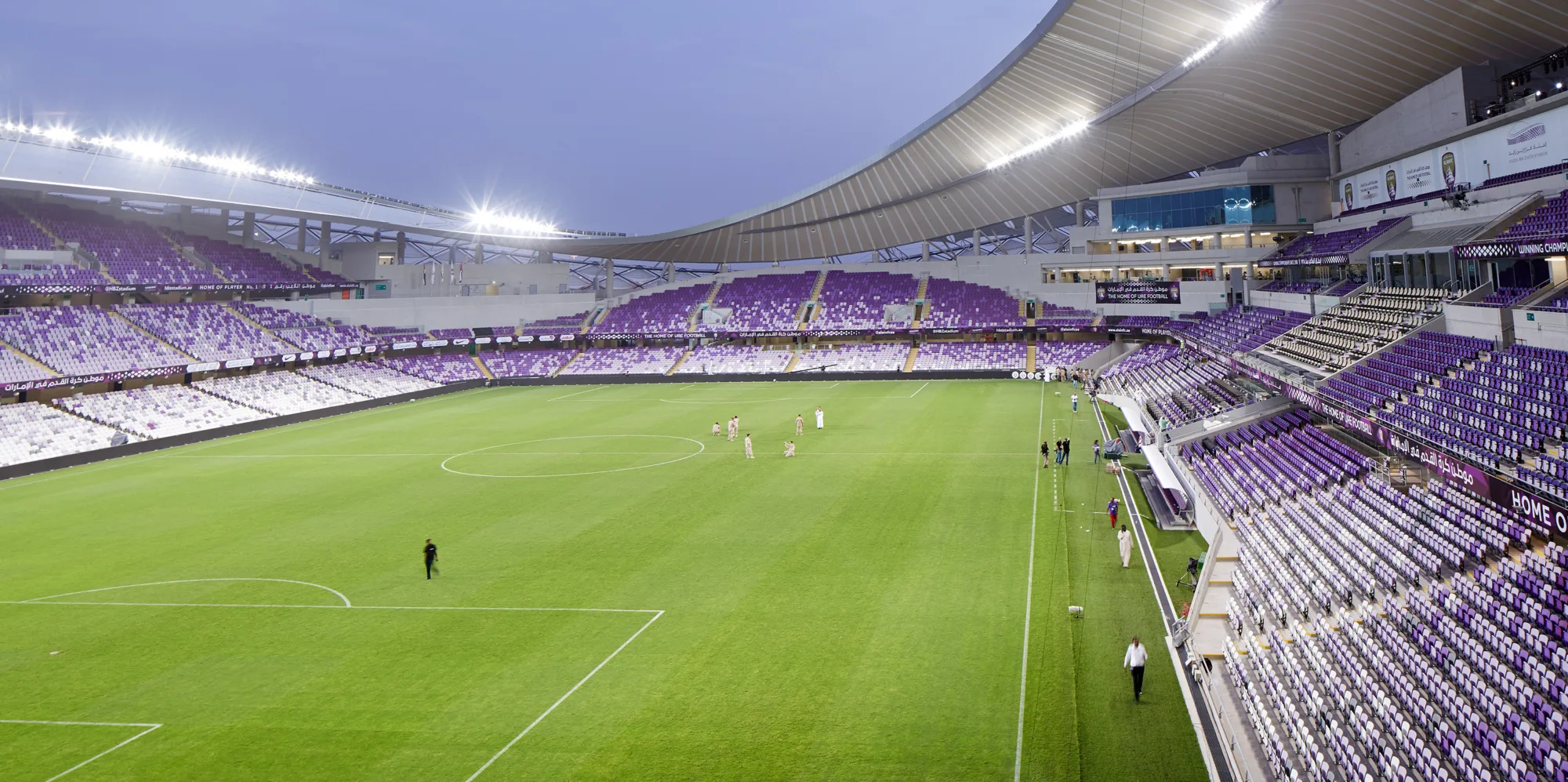 Al Ain football stadium at dusk, with evening lighting and empty seating