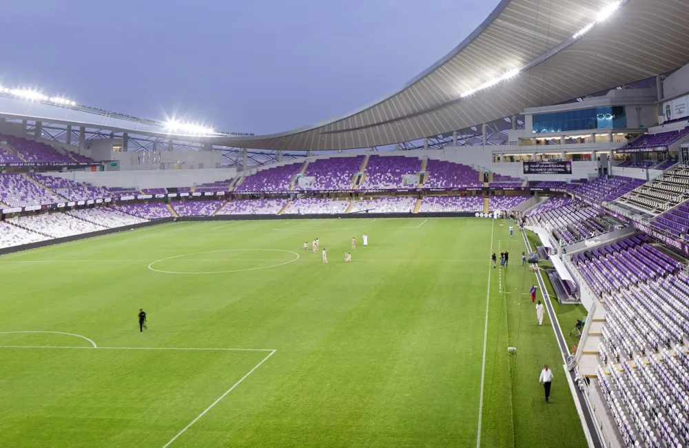 Al Ain football stadium at dusk, with evening lighting and empty seating