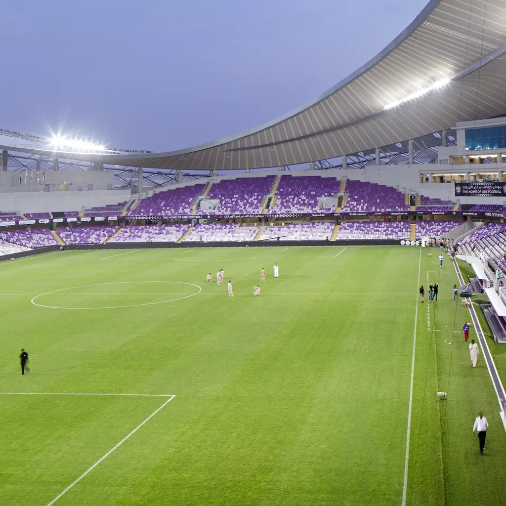 Al Ain football stadium at dusk, with evening lighting and empty seating
