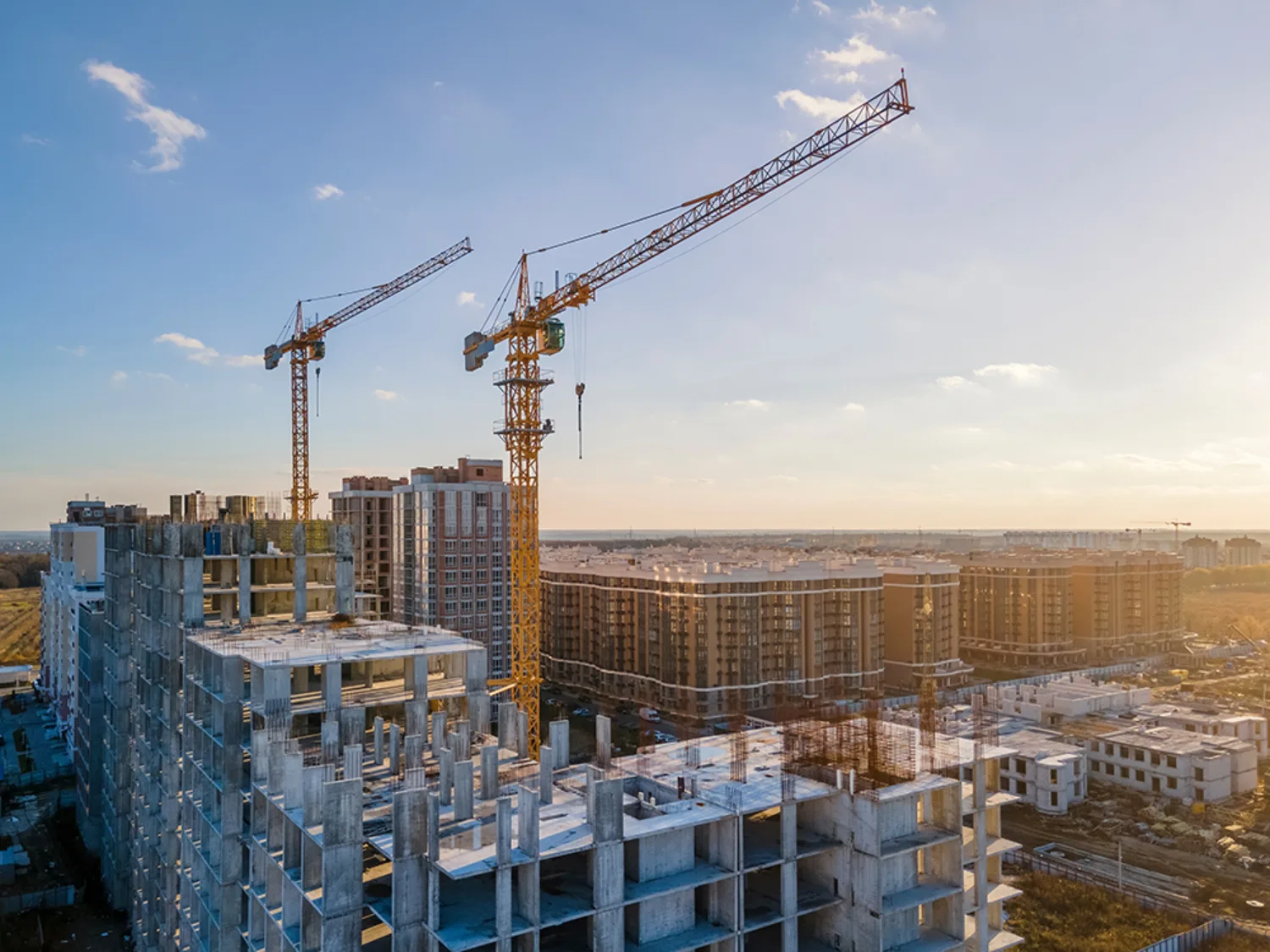 City construction city half built buildings with yellow cranes and a sunny and blue sky