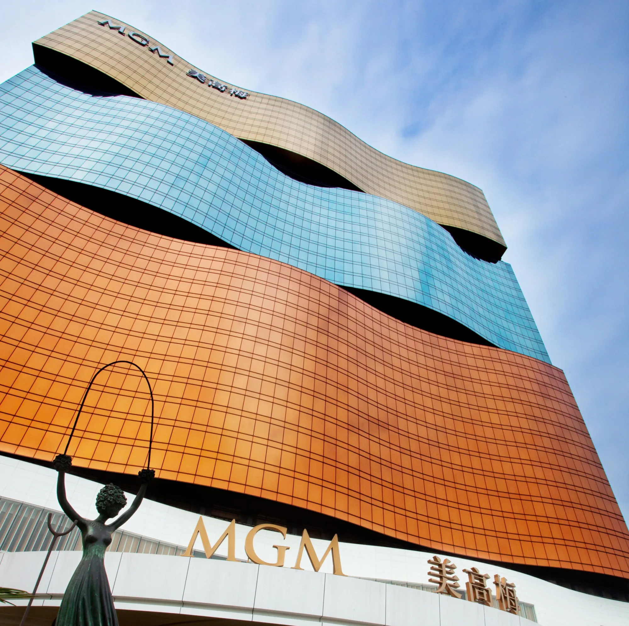 Looking up at the MGM Grand exterior with blue skies and a statue outside