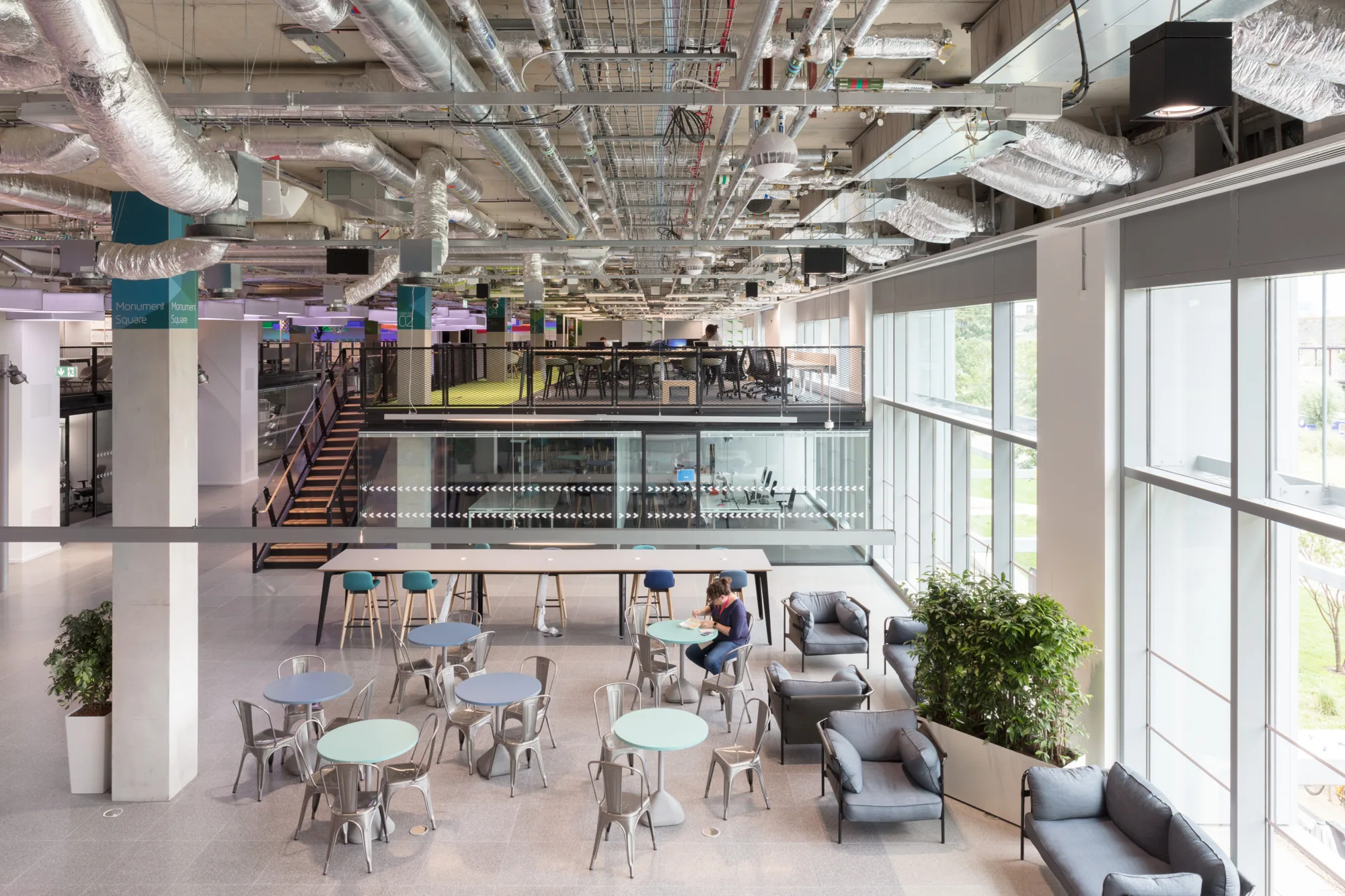 Plexal office interior with desks, exposed ceiling beams and glass façade