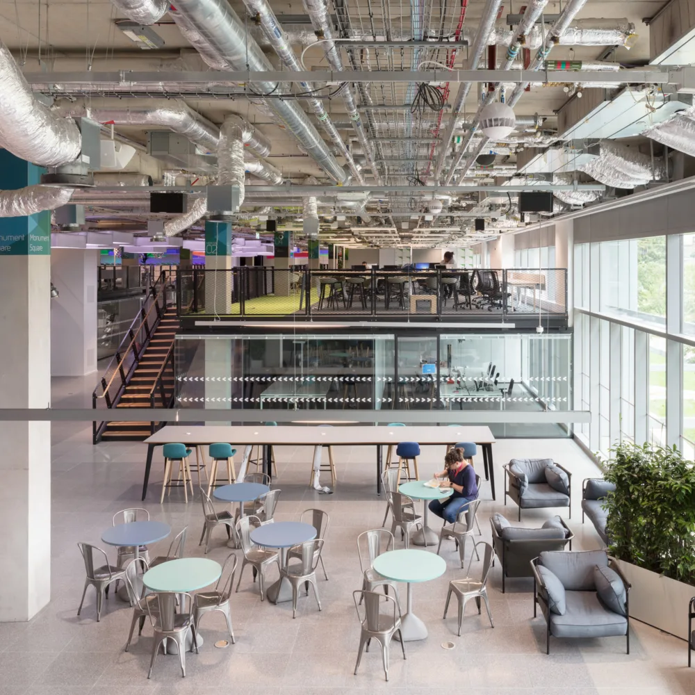 Plexal office interior with desks, exposed ceiling beams and glass façade