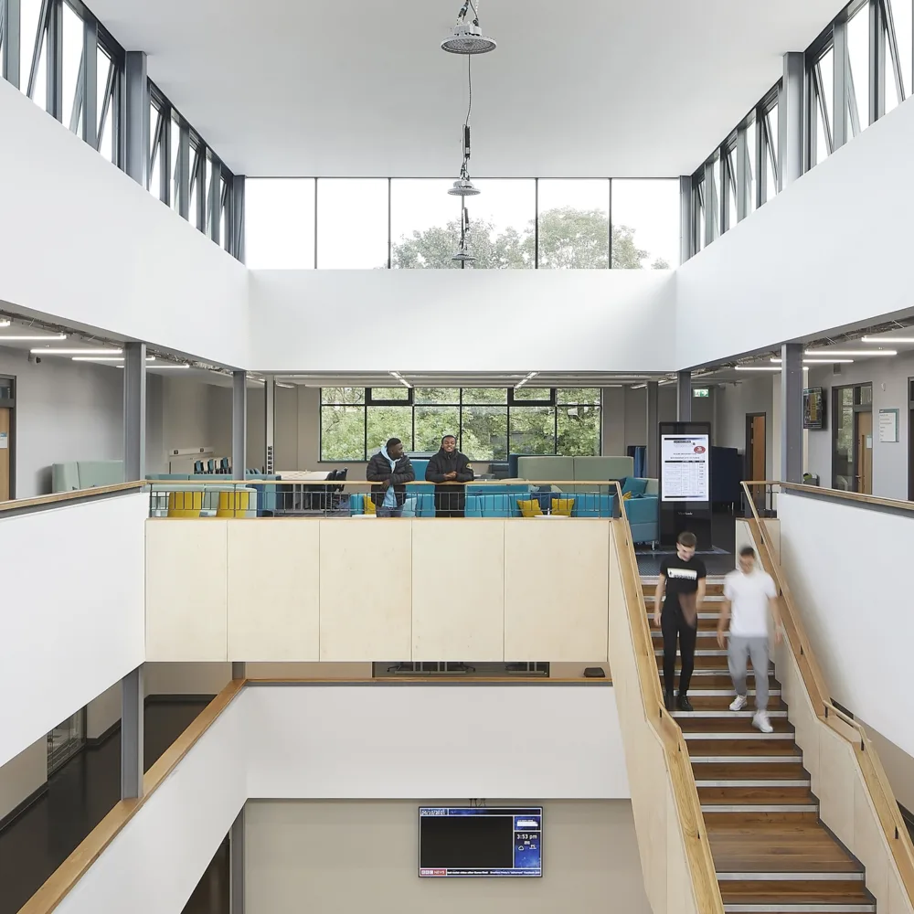 Interior of a large open lobby with wooden and white staircases