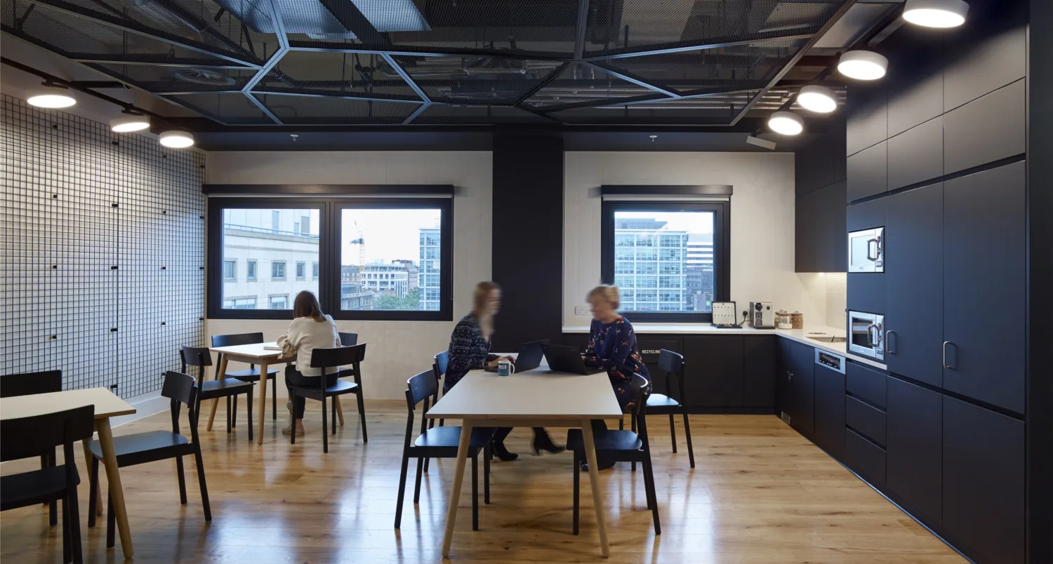 Café area in office with seating, windows and subtle lighting