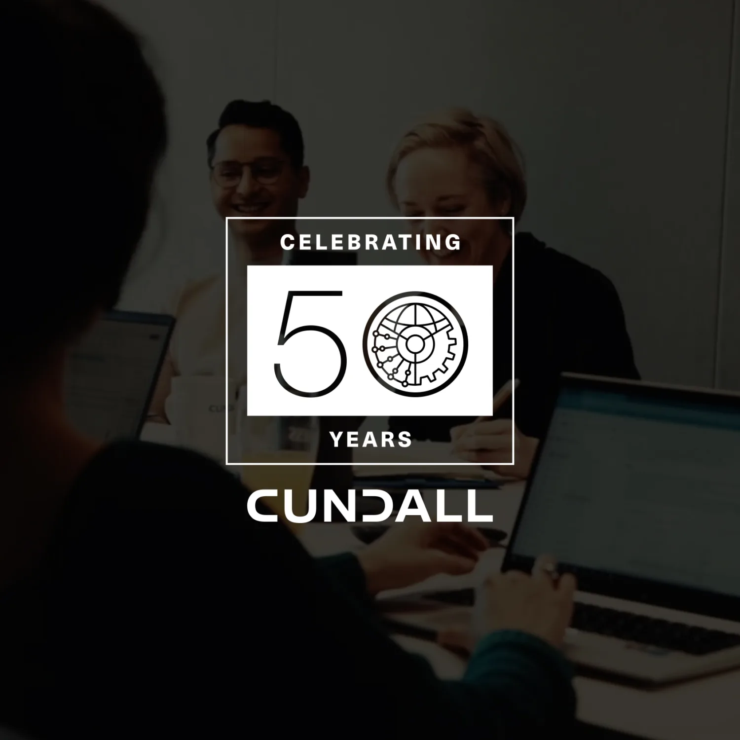 A group of people seated around a meeting table with laptops and notebooks in a modern office setting. Overlaid graphic reads “Celebrating 50 Years Cundall” with a gear and circuit design.