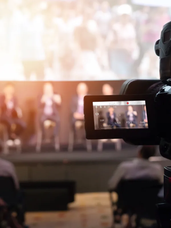 Panel sat on stage presenting in front of an audience and being filmed