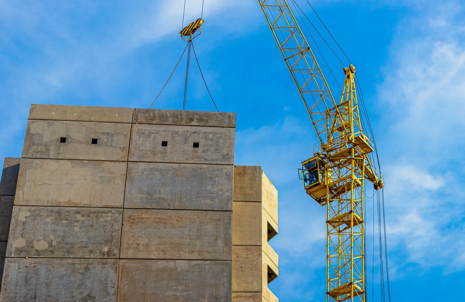Elements that have been constructed offsite being lifted by a yellow crane