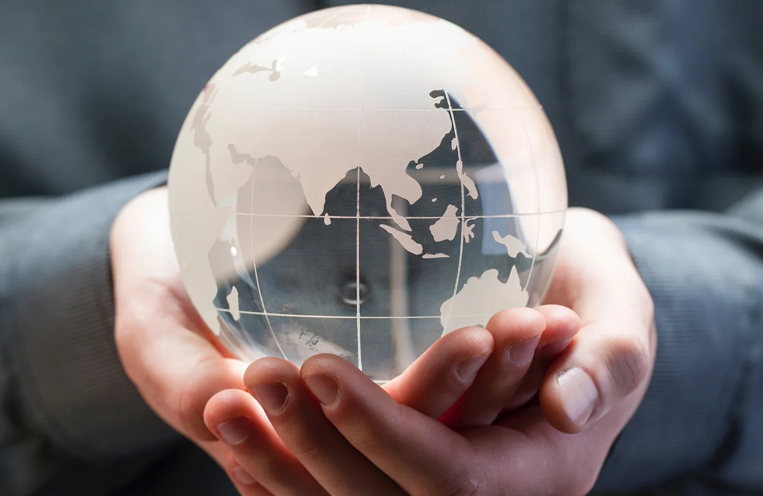 Cupped hands holding a glass globe