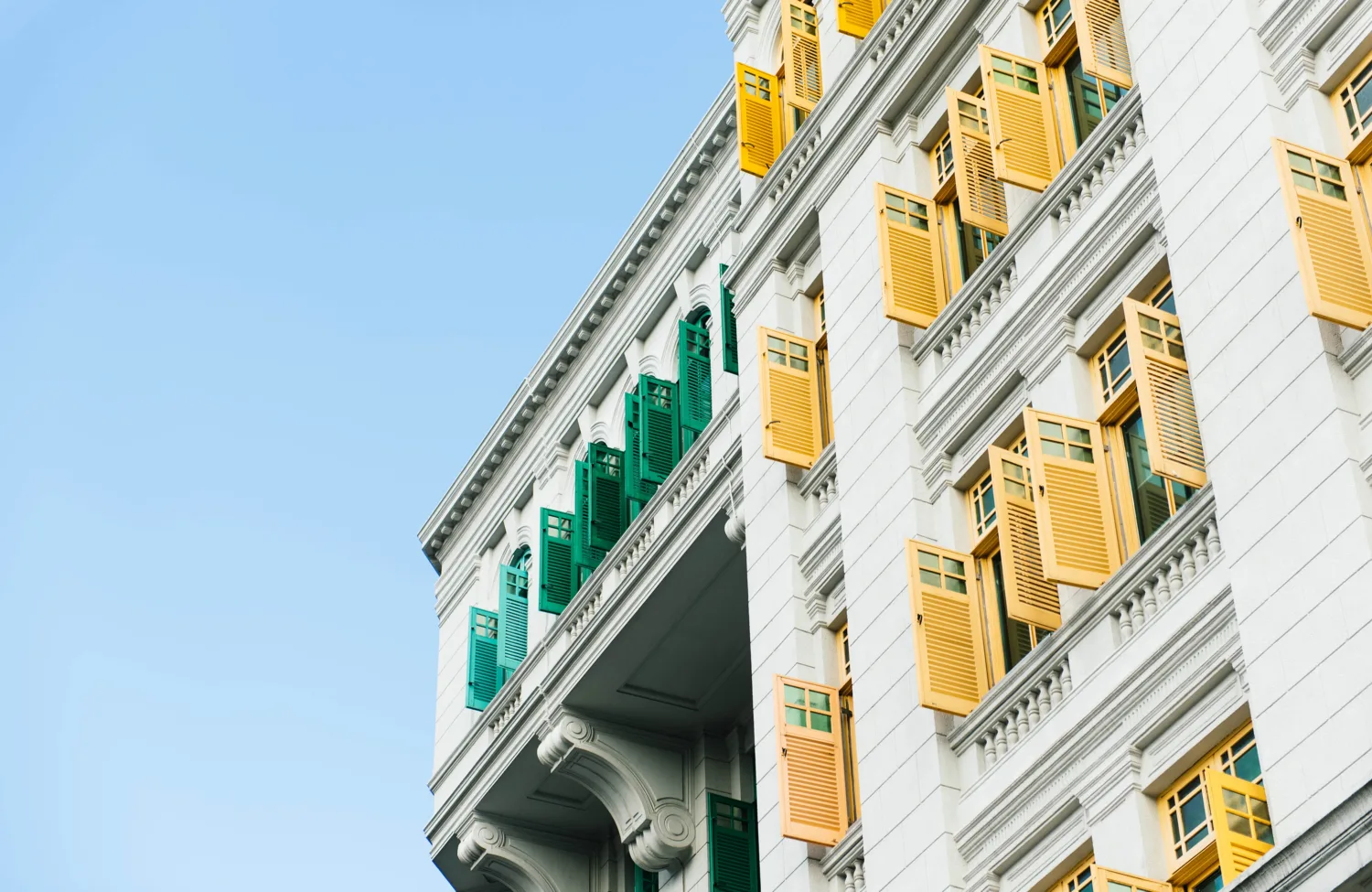 White building with yellow and green shutters against a blue sky